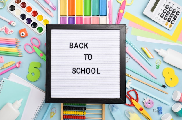 Material de escritório plano leigo. De volta à escola. Vários materiais de escritório em um fundo azul claro com uma placa de feltro.