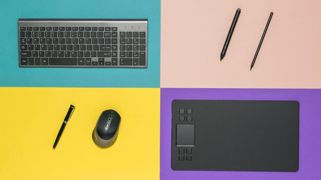 Material de escritório, teclado e mesa gráfica em um espaço multicolorido. dispositivos periféricos para computadores.