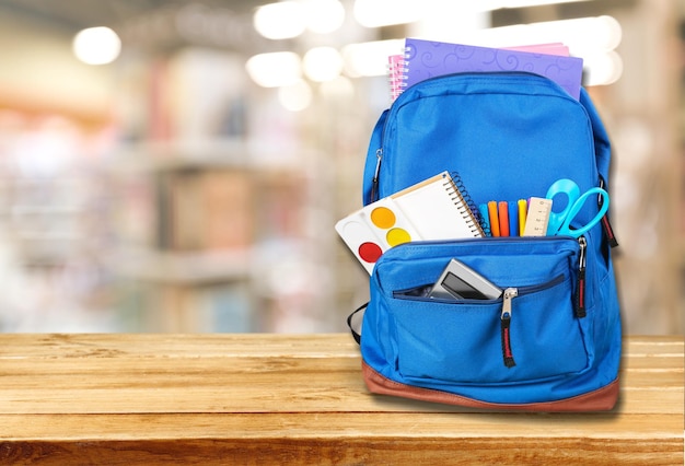 Material escolar colorido na mochila no quadro-negro