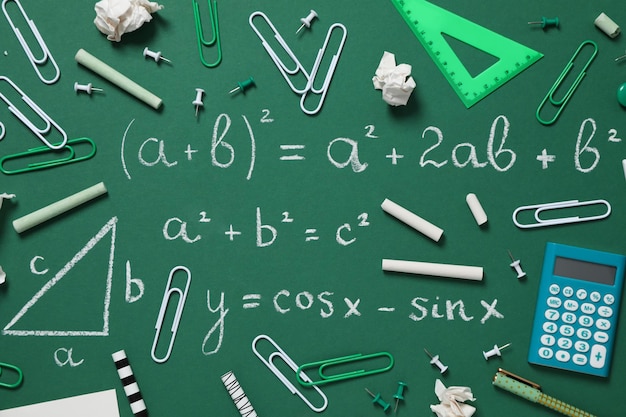 Material escolar em um conselho escolar com uma fórmula escrita em giz
