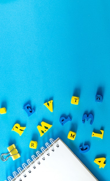 Material escolar sobre um fundo azul. conceito de dia de escola e professor. letras de madeira na mesa com espaço de cópia.