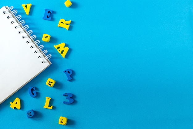 Foto material escolar sobre um fundo azul. conceito de dia de escola e professor. letras de madeira na mesa com espaço de cópia.