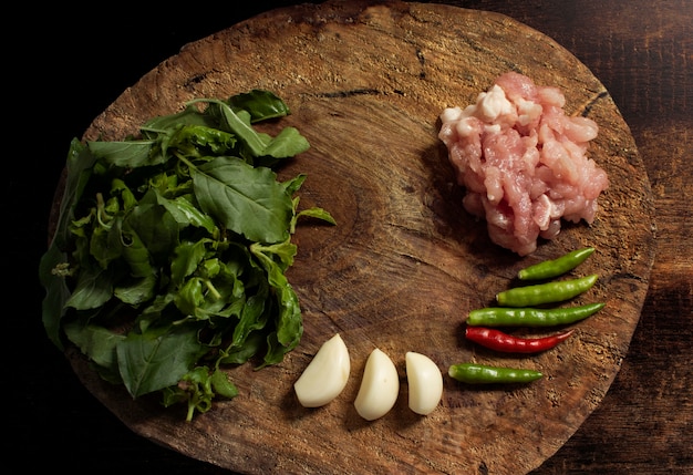 Material für das Kochen des Aufruhrs gebratenes Schweinefleisch und des Basilikums auf hölzernem hackendem Brett.