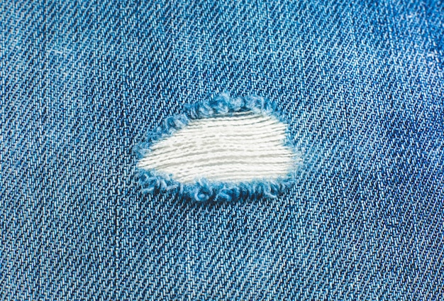 Material de jeans azul rasgado hipster. Textura de tela de mezclilla destruida. De cerca.