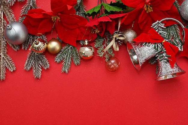 Material de Navidad, campanas y X'mas Decoraciones de flores y bolas sobre un fondo rojo.