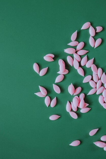 Foto materiales para la depilación de cejas gránulos de cera rosa sobre fondo verde