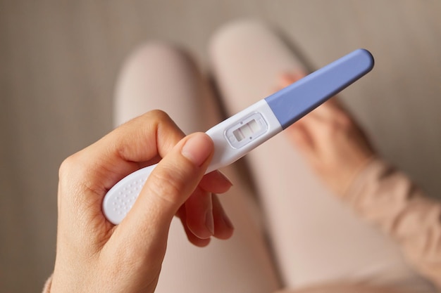 Foto maternidade fértil mulher não reconhecível segurando a mão teste de gravidez com duas listras resultado positivo futura mãe à espera do parto