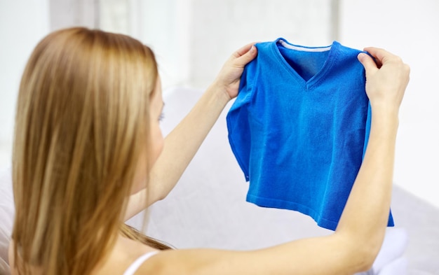 Maternidade, pessoas e crianças conceito de vestuário - mulher feliz segurando e olhando para meninos camisola azul em casa