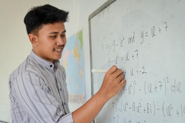 Mathematiklehrer schreibt Formeln auf Whiteboard im Klassenzimmer