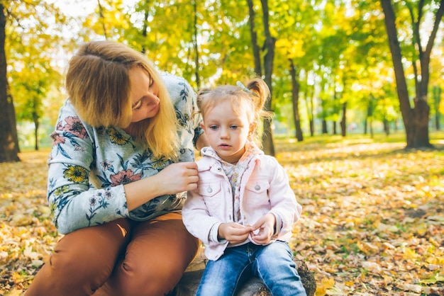 Mather com filhinha brincando no parque público da cidade de outono