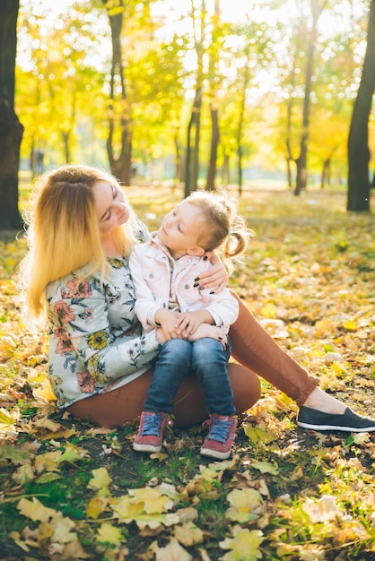 Mather com filhinha brincando no parque público da cidade de outono