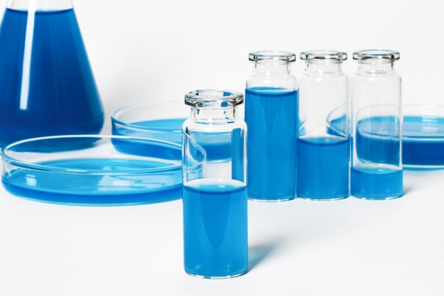 Un matraz un frasco para un laboratorio con un líquido azul azul Contra el fondo de cristalería de laboratorio Placas de Petri matraces tubos de ensayo Sobre un fondo de luz blanca