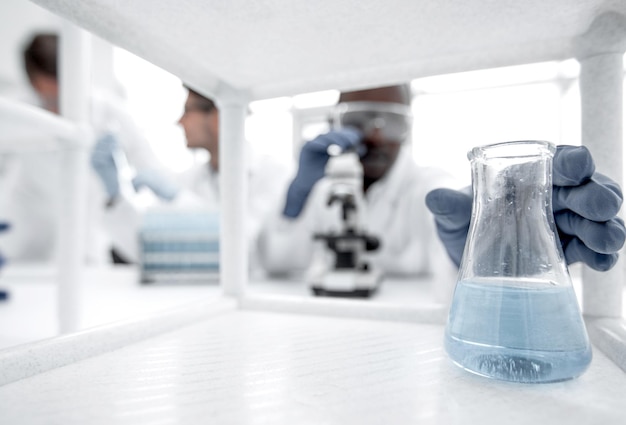 Matraz con líquido azul sobre la mesa de laboratorio