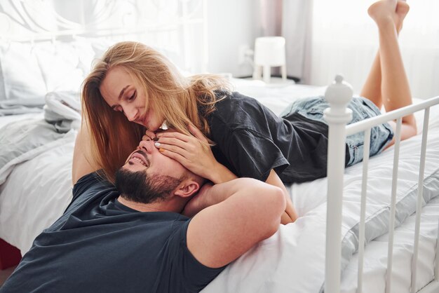 Matrimonio joven besándose en el dormitorio durante el día.