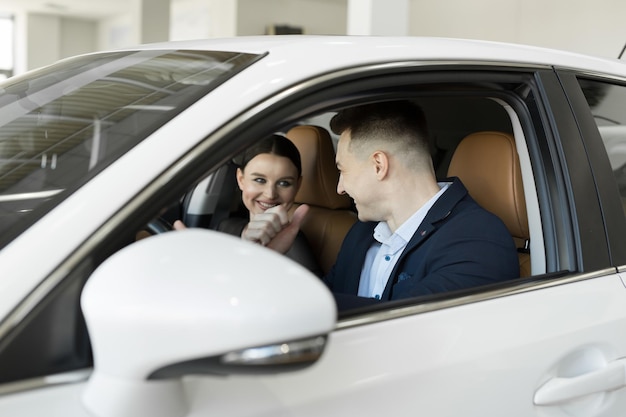 Matrimonio marido y mujer sentados en un coche en un concesionario de coches. Prueba el coche antes de comprarlo.