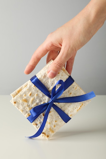 Matzo mit Band in der Hand auf hellem Hintergrund