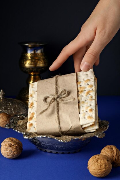 Matzo en nueces de mano y taza sobre un fondo azul oscuro