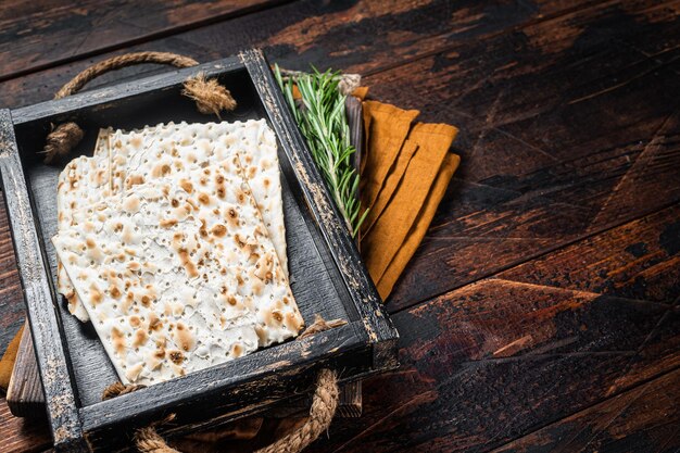 Matzos de páscoa de celebração com pão sem fermento matzo em uma bandeja de madeira com ervas Fundo de madeira Vista superior Copiar espaço