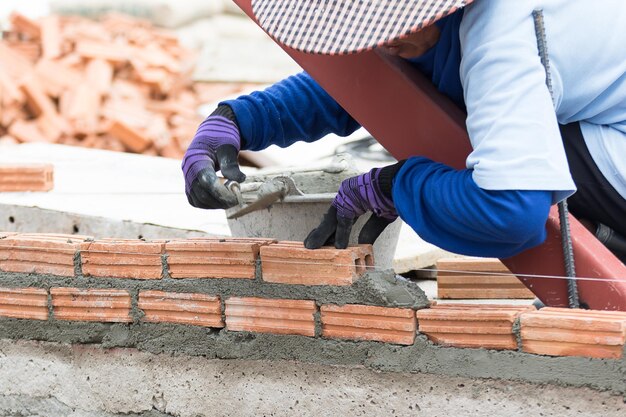 Foto maurer arbeitet auf der baustelle einer mauer aus ziegelsteinen