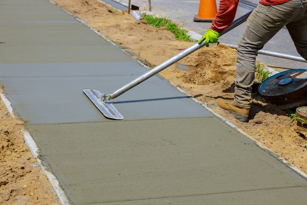 Maurer baut einen estrichmantel zement ein arbeiter schwimmt einen neuen beton gehsteig