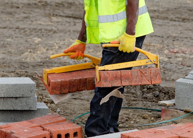 Maurer bringen Ziegel mit Ziegelhebern in die Nähe seines Arbeitsplatzes