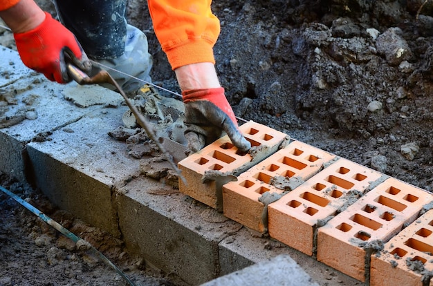 Maurer in orange hiviz, der ziegel auf baustelle legt