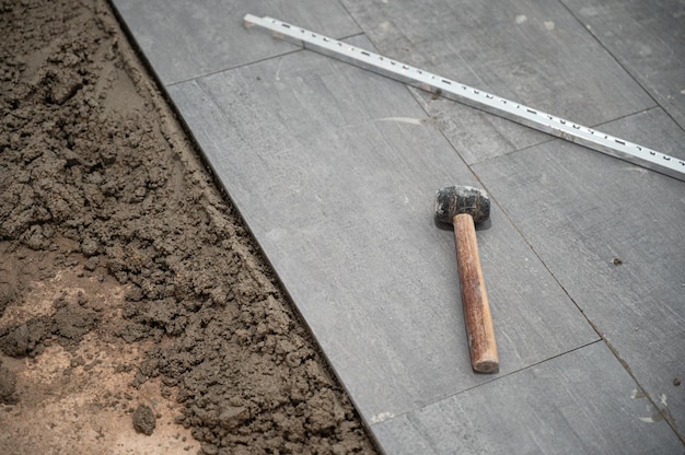 Mazo y herramientas sobre baldosas de granito durante la colocación del piso
