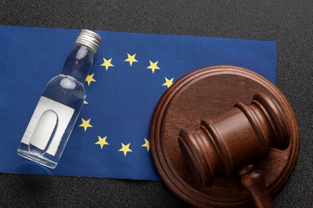 Mazo de juez de madera y botella de alcohol Fondo de bandera de la UE Demanda de alcohol en concepto de Unión Europea