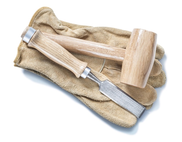 Mazo de madera y cincel en guantes de cuero blanco aislado
