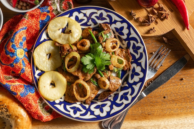 Foto mazza. heißes usbekisches lammlebergericht mit bratäpfeln, paprika, knoblauch, koriander, frühlingszwiebeln und sojasauce.