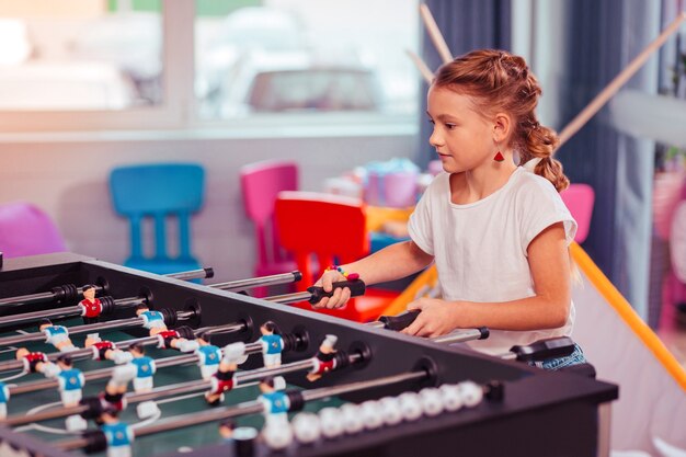 Me ajude. Linda garota em pé na semi-posição e jogando o jogo de mesa com prazer