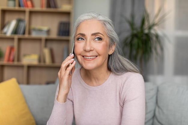 Me alegro de que una anciana europea sonriente con canas llame por teléfono y tenga buenas noticias en el interior de la habitación