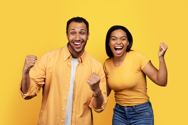 Me alegro de que la joven pareja afroamericana grite diviértase y haga el signo de éxito con la mano en el tiempo libre