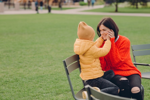 Me alegro de que la madre y la hija se sientan en chiar al aire libre, tienen expresiones positivas