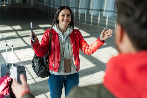 Me alegro de verte. Feliz mujer llena de alegría yendo a su esposo mientras se reunía en el salón del aeropuerto después de volar. Concepto de viajes y viajes.