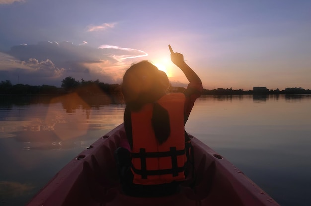 Me encanta la aventura en la naturaleza, el niño del patio trasero apunta al amanecer en un bote en kayak