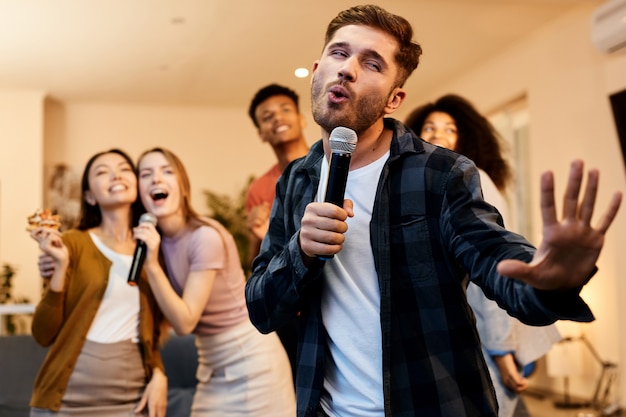 Me encanta cantar entusiasta joven guapo cantando con micrófono mientras juega karaoke con