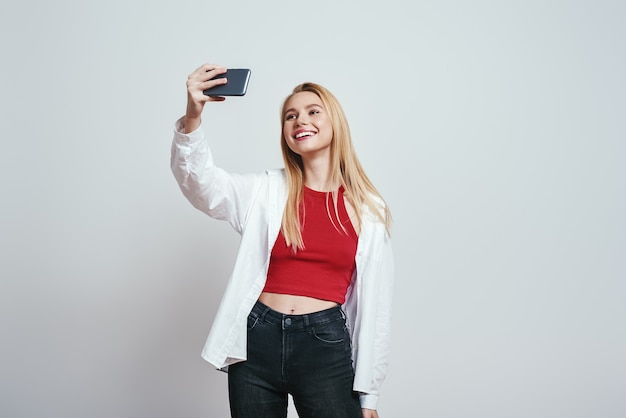 Me encanta selfie linda mujer joven con cabello rubio haciendo selfie por su teléfono inteligente y