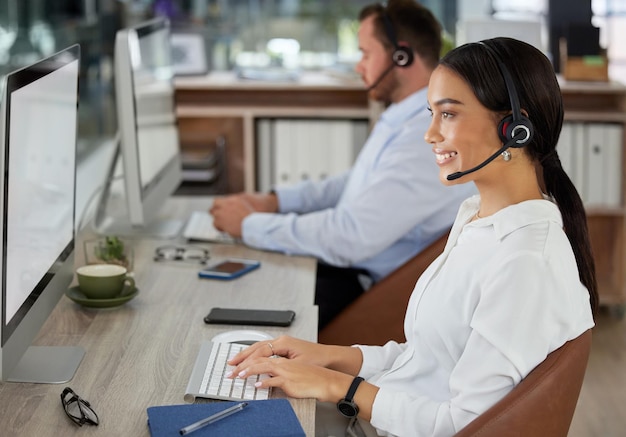 Me ocuparé de eso de inmediato. Foto de una mujer joven que usa un auricular y una computadora en una oficina moderna.