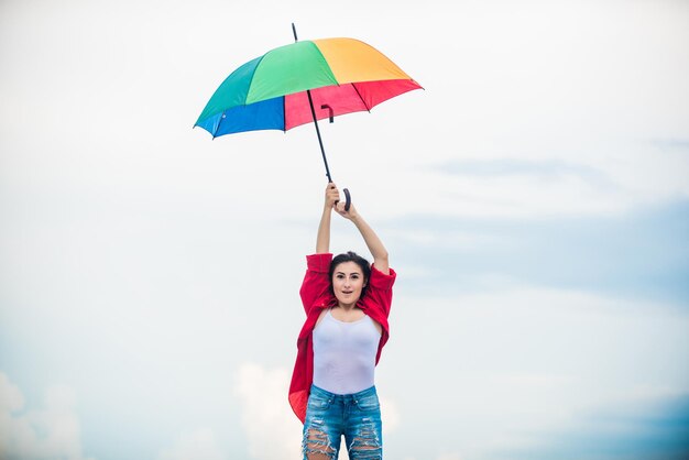 Me sentindo confortável. previsão do tempo no outono. mulher bonita com guarda-chuva colorido. tempo chuvoso. Queda de humor positivo. gasto de tempo despreocupado. moda outono. Proteção de guarda-chuva arco-íris.