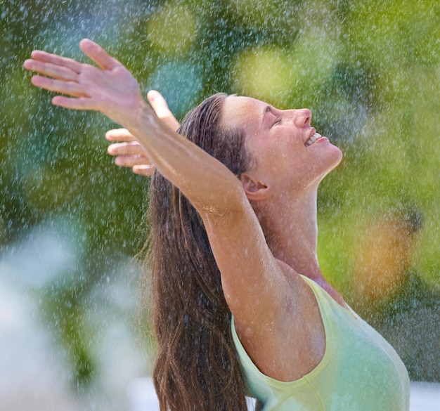 Me siento vivo Vista lateral de una mujer joven de pie felizmente bajo la lluvia