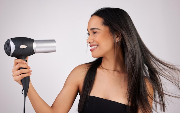 Me sorprendes Foto de una mujer joven sosteniendo un secador de pelo mientras está de pie contra un fondo gris