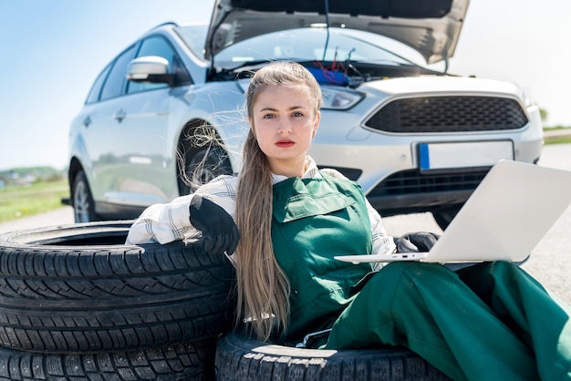 Mecânica de mulher com carro quebrado e laptop