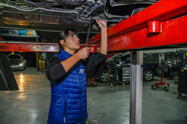 Mecánica de sexo femenino joven que trabaja en la reparación de un motor de coche