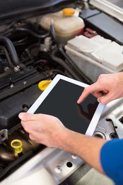 Mecânica usando o tablet para consertar o carro