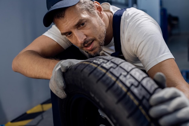 Foto mecânico adulto médio, verificando a profundidade do pneu do carro na oficina de reparação automóvel