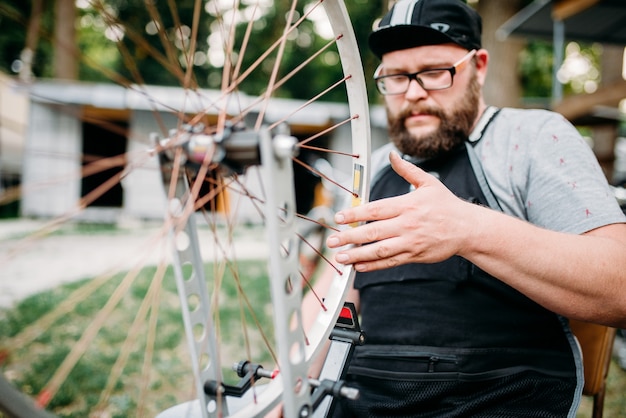 El mecánico ajusta los radios de la bicicleta y repara la rueda