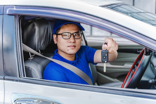 Mecânico asiático dando as chaves do carro sentado no carro