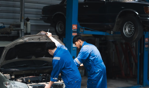 Mecánico asiático reparando un coche en taller de reparación de automóviles