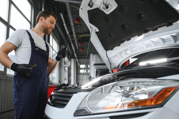 Mecánico automático que verifica el nivel de aceite en el motor del automóvil inspecciona el concepto de varilla de medición del nivel de agua del motor de verificar el nivel de aceite del motor cada vez antes de irse